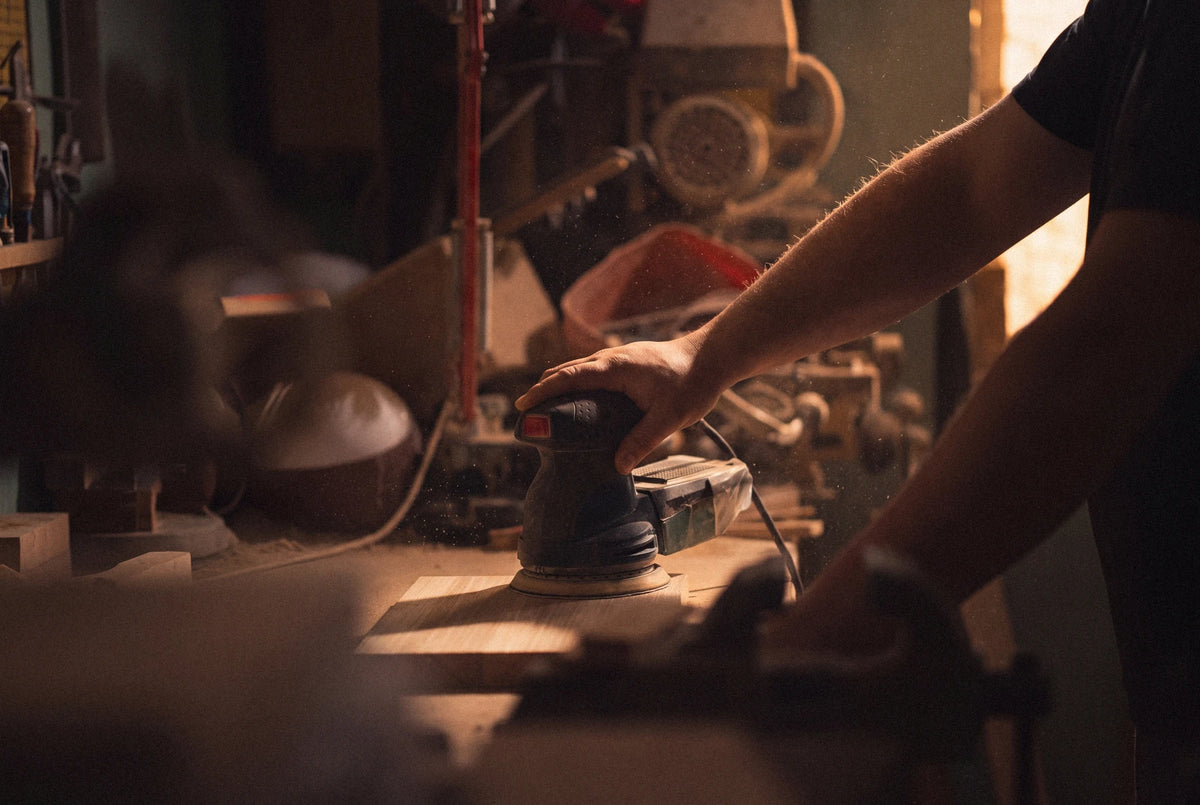 Hand sanding a wooden board in the Runewood workshop